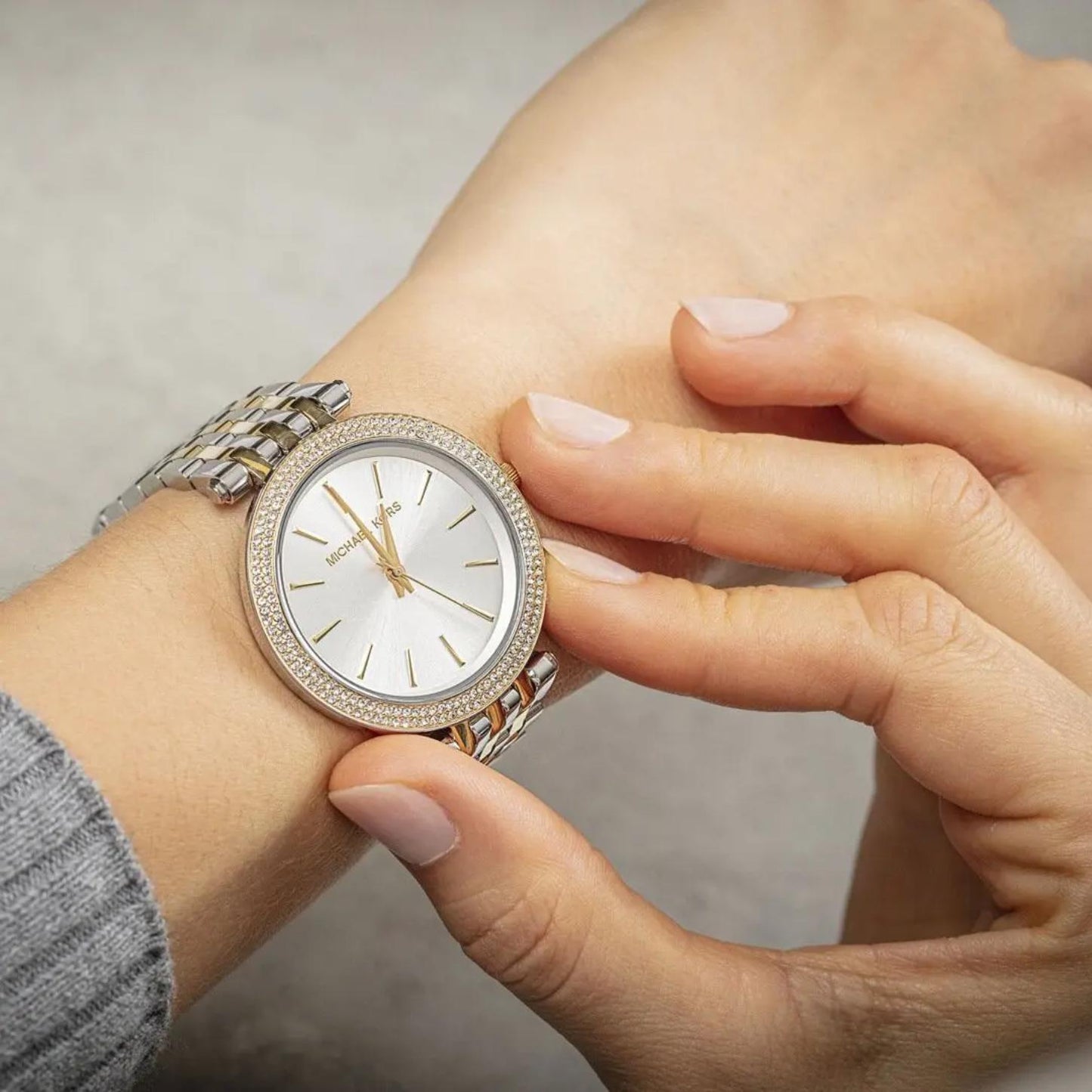 Michael Kors Darci MK3215 women’s watch worn on wrist with white sunray dial, crystal-set bezel and two-tone stainless steel bracelet in close-up view.