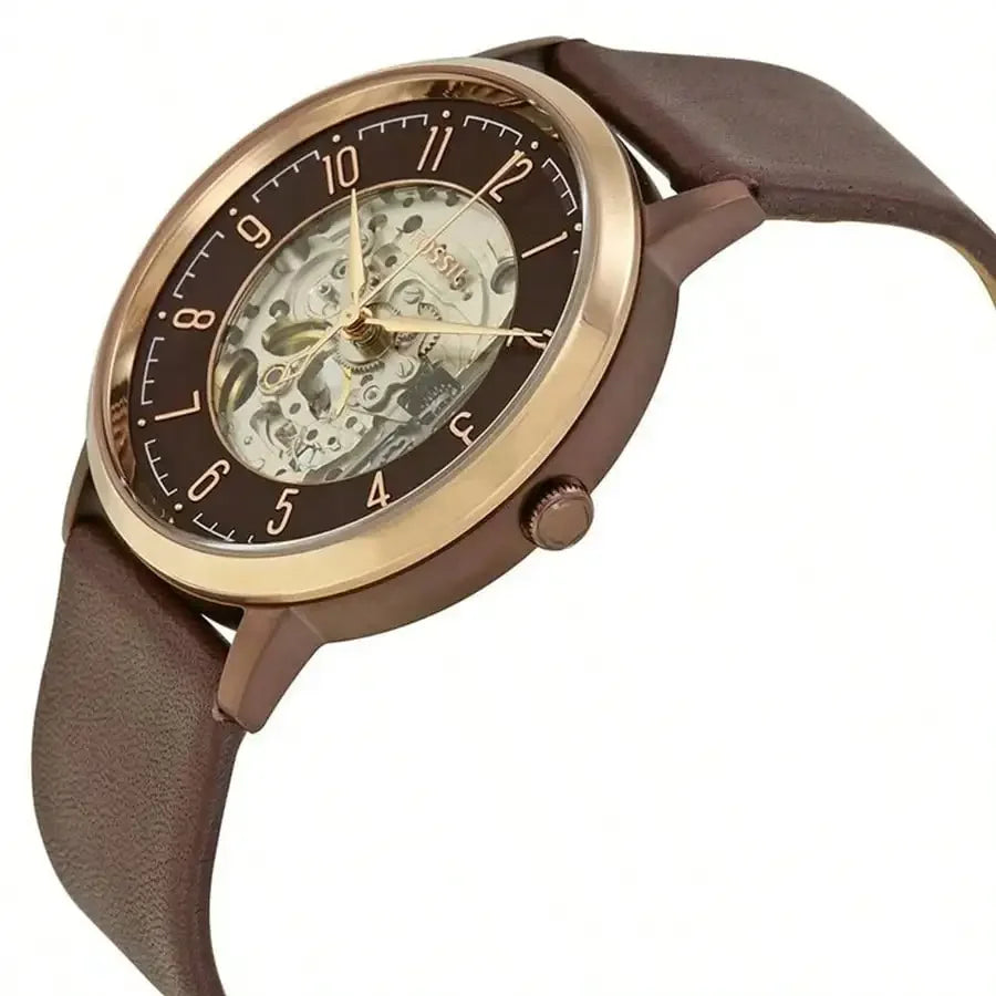 Reloj Fossil ME3131 automático skeleton, vista angulada, caja color cobre/oro rosa, esfera abierta y correa marrón, detalles elegantes.