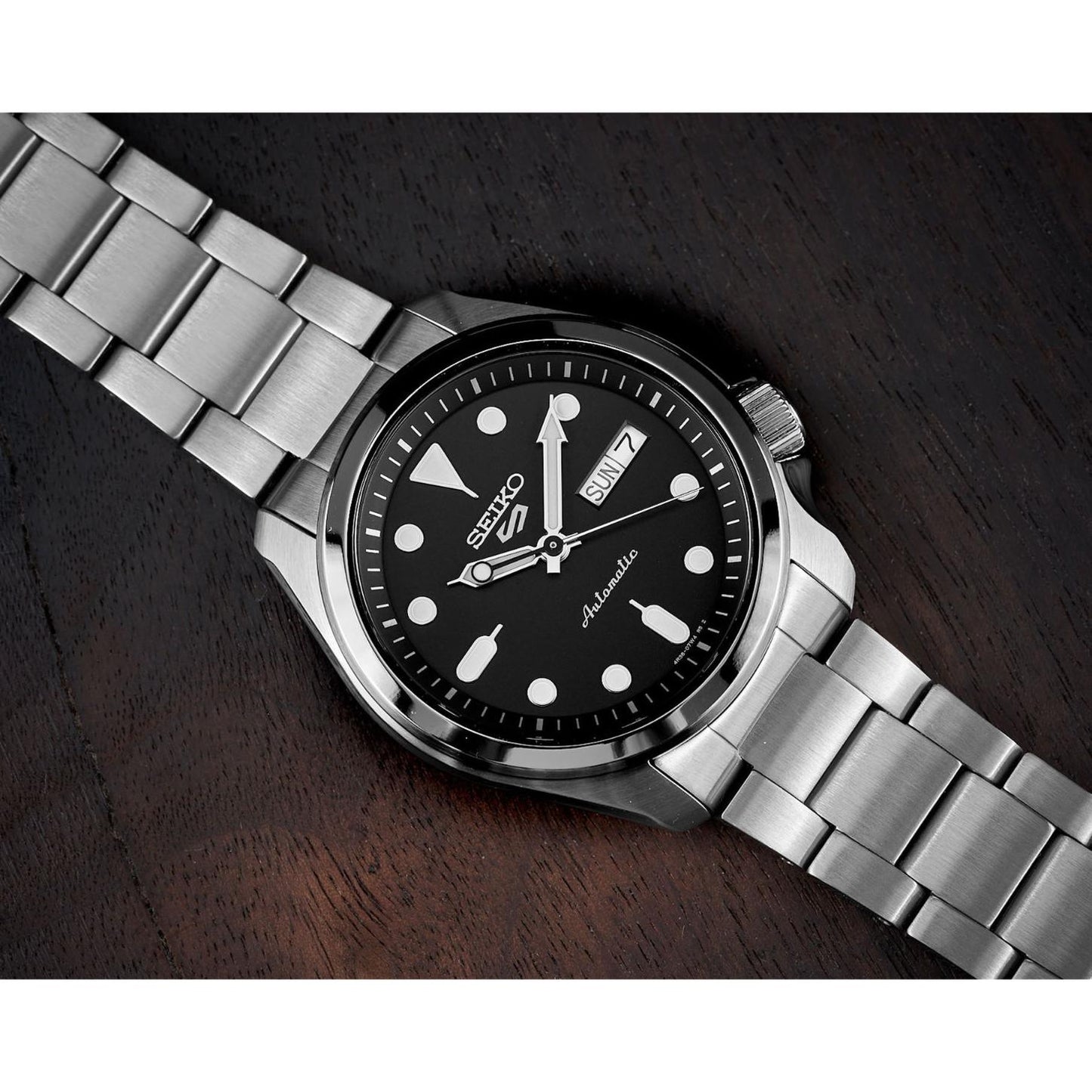 Seiko 5 Sports SRPE55K1 with black dial, luminous hour markers, day-date display, side crown, stainless steel case, and stainless steel bracelet.