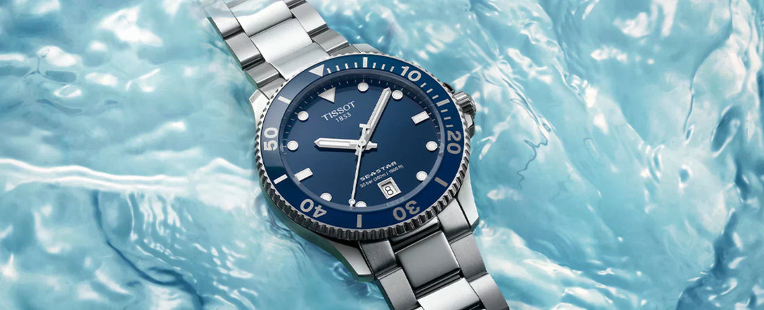 Blue Tissot dive watch with a stainless steel bracelet placed over a water background.