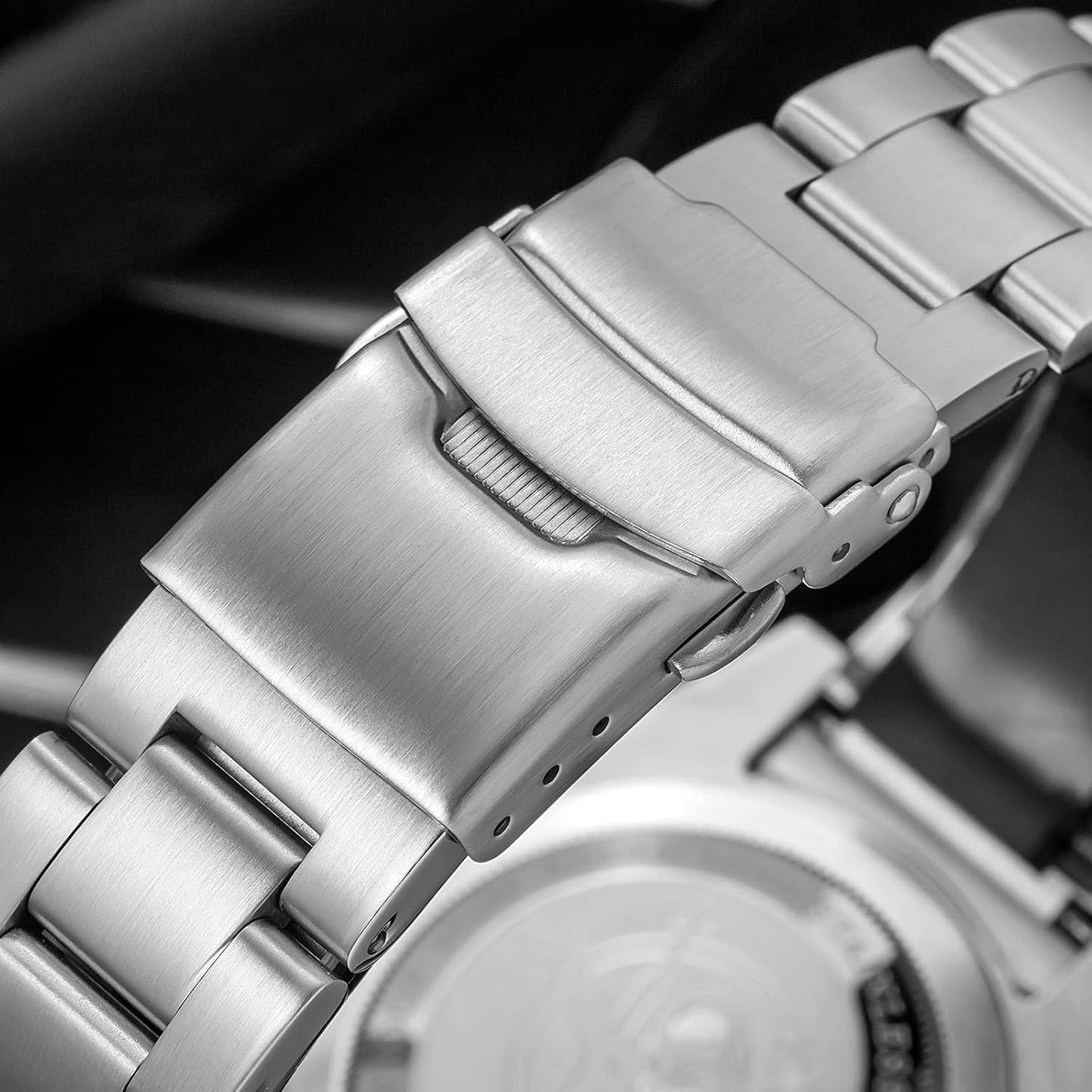 Primer plano del cierre del brazalete de acero del reloj Addiesdive, mostrando el mecanismo abatible y los eslabones metálicos en acabado cepillado.