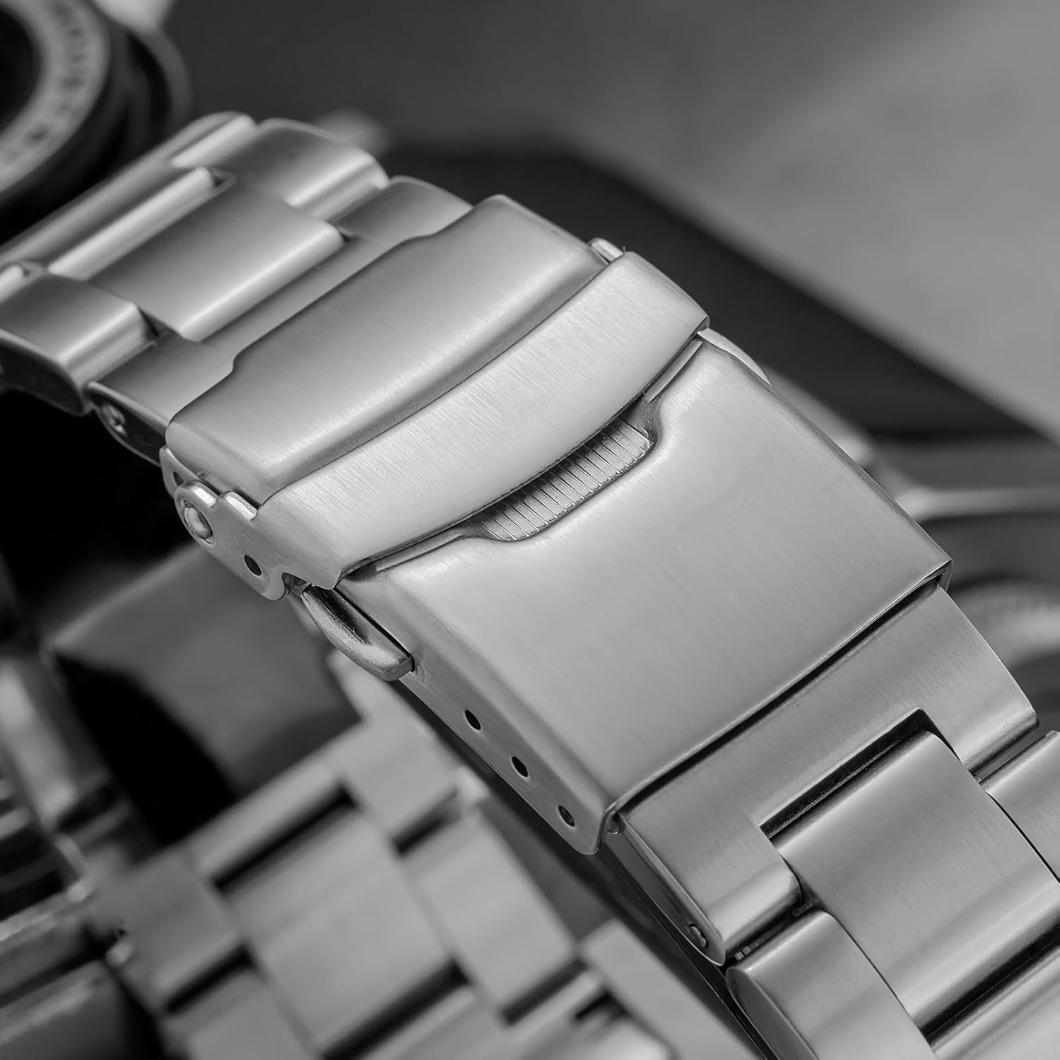 Detalle del cierre del brazalete de acero del reloj Addiesdive, mostrando el mecanismo abatible y los eslabones metálicos.