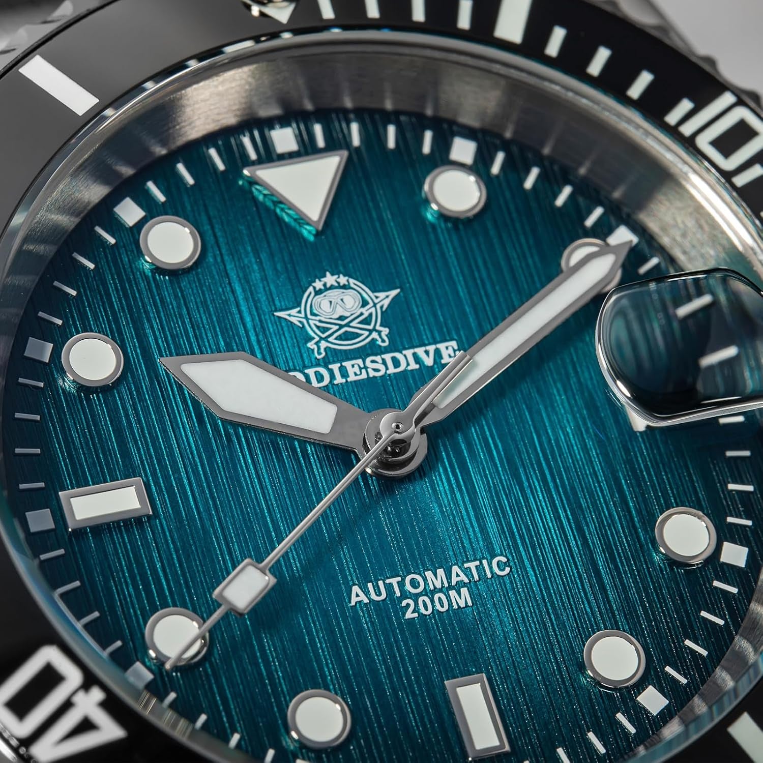 Primer plano de la esfera azul del reloj Addiesdive automático, mostrando los índices luminiscentes, las agujas metálicas y la lupa sobre la ventana de fecha.