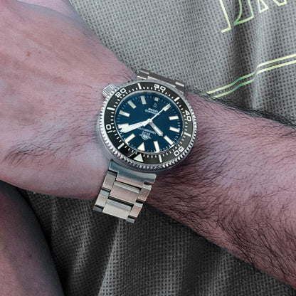 Reloj Addiesdive automático de acero con esfera negra lucido en la muñeca de una persona sobre camiseta deportiva.