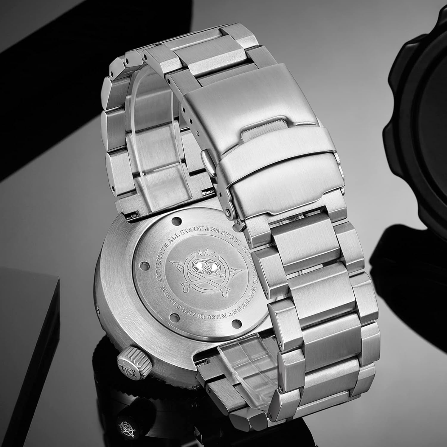 Reloj Addiesdive automático de acero mostrado en vista trasera sobre superficie oscura, destacando el grabado de la tapa y el brazalete.