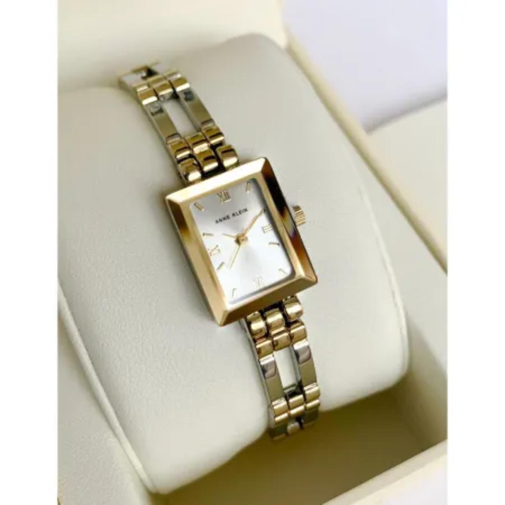 Reloj Anne Klein 10/4899SVTT sobre cojín en su caja original, caja rectangular dorada y brazalete bicolor oro y plata