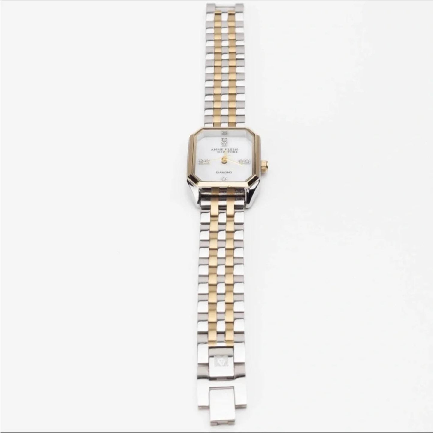 Anne Klein 12/7751MPTT with white mother-of-pearl dial, gold-tone bezel accents, and two-tone bracelet with open jewelry clasp.
