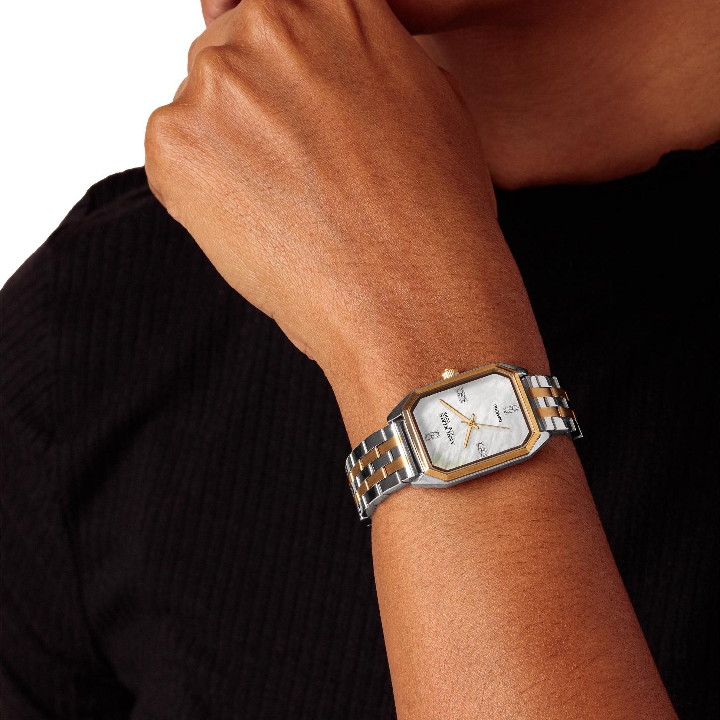 Anne Klein 12/7751MPTT with white mother-of-pearl dial, diamond accent markers, gold-tone bezel details, and two-tone bracelet worn on the wrist.