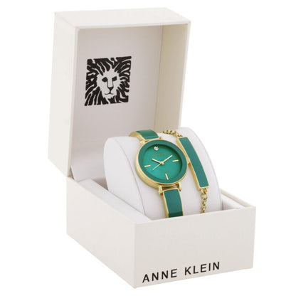 Anne Klein AK/3620GNST gift set with green dial watch, gold-tone case, green enamel bracelet, matching green accent bracelet, white display cushion, and open Anne Klein presentation box.