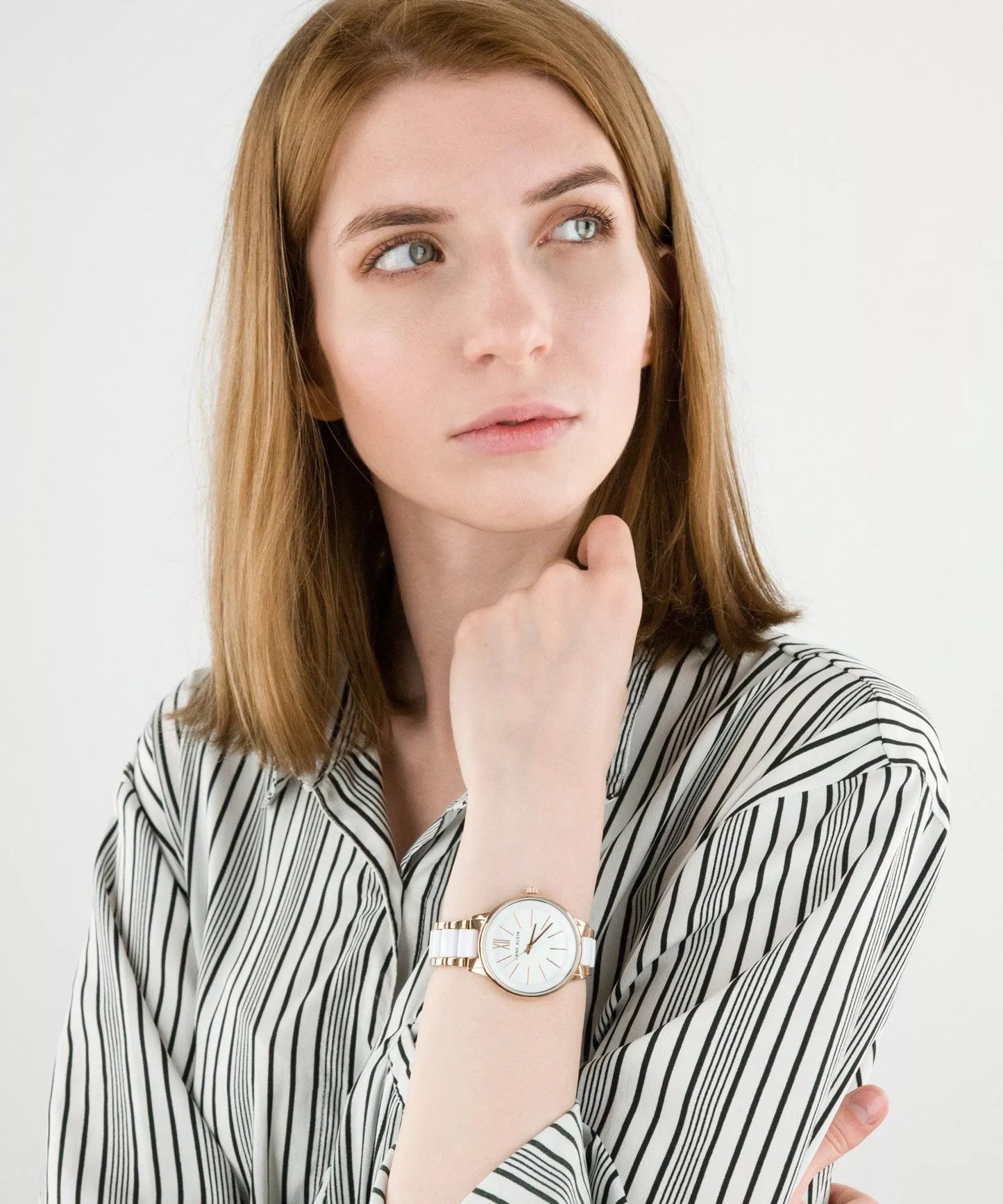 Reloj Anne Klein AK/1412WTRG en muñeca de mujer, brazalete blanco y oro rosa combinado con camisa de rayas