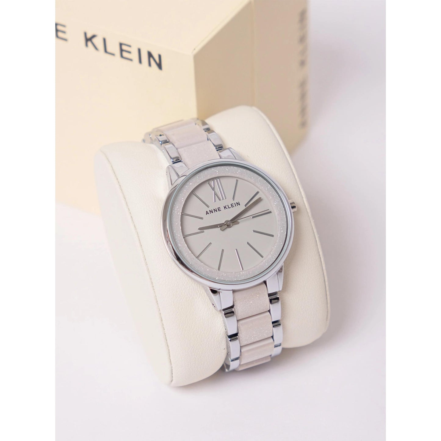 Anne Klein AK/1413LGSV with grey sunray dial, glitter bezel detail, and metallic silver bracelet displayed on a presentation cushion.