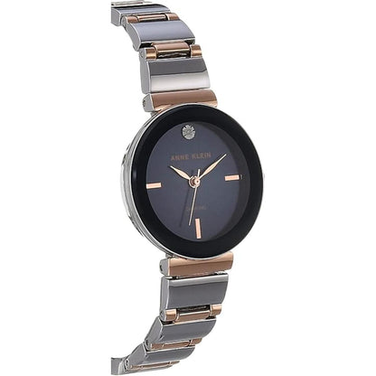 Anne Klein AK/2435NVRT with dark blue dial, rose gold-tone hands and markers, diamond accent at 12 o’clock, and two-tone bracelet in angled view.