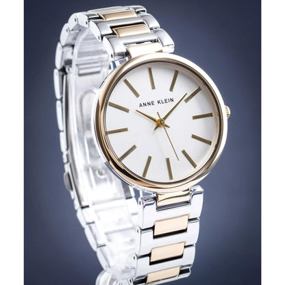 Reloj Anne Klein AK/2787SVTT en vista tres cuartos, esfera blanca y brazalete bicolor plata y dorado sobre fondo gris.