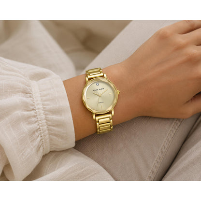 Woman wearing the Anne Klein AK3966CHGB gold-tone dress watch with a champagne dial and diamond accent, showcasing its elegant slim profile and polished gold-tone bracelet in an everyday lifestyle setting.
