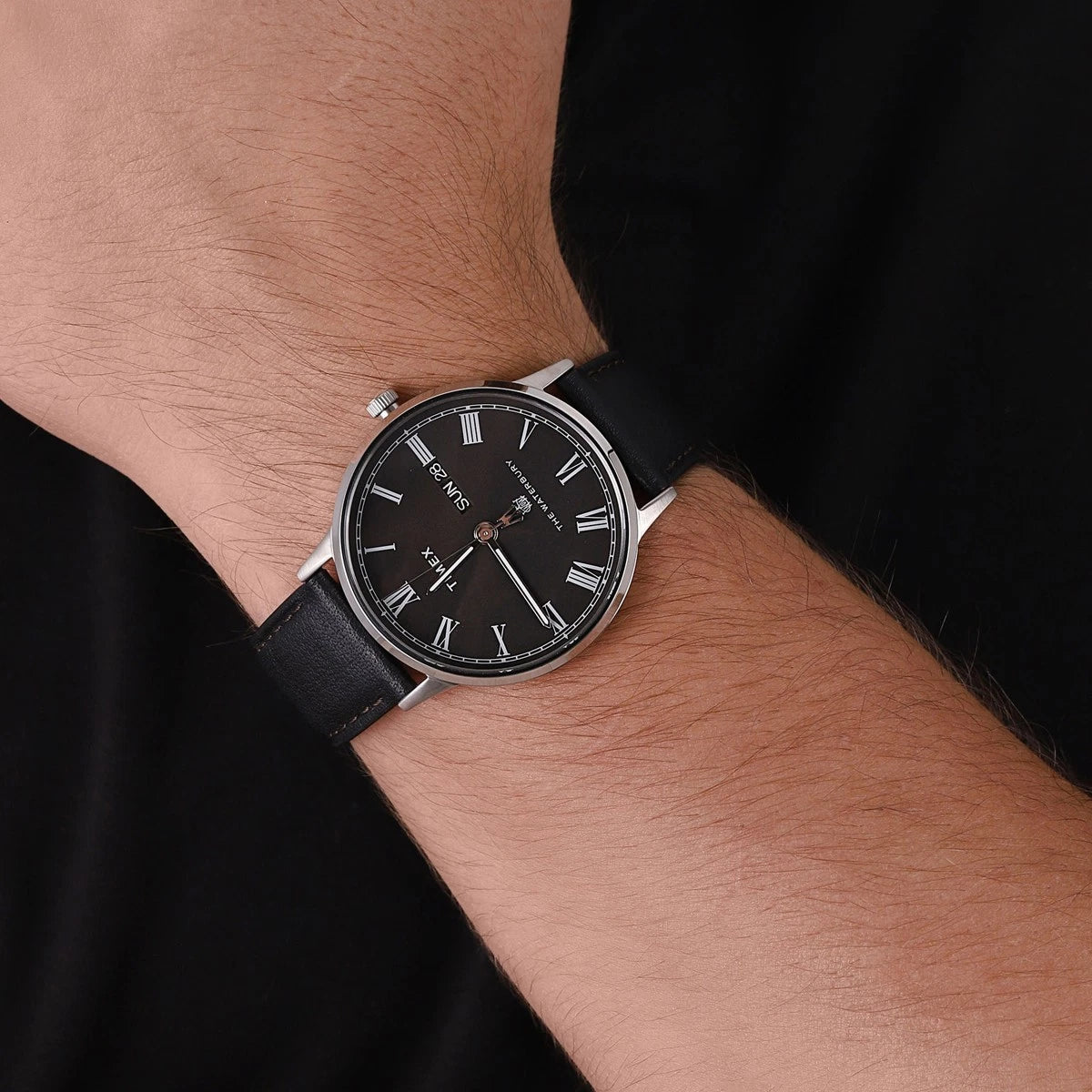 Reloj Bering para hombre con esfera negra, números romanos y correa de piel negra, visto en la muñeca.