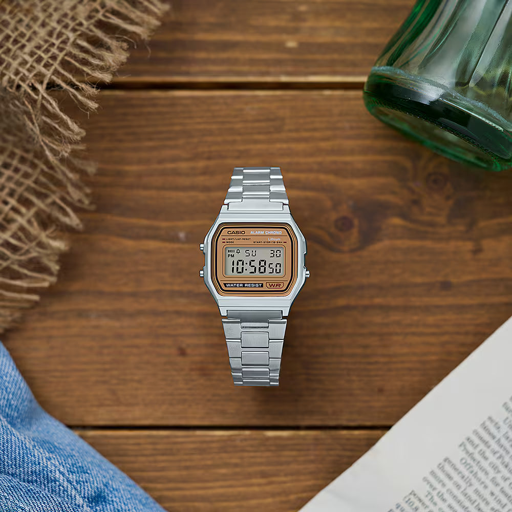 Casio Digital Classic vintage watch with digital display and stainless steel bracelet shown in lifestyle setting on wooden surface.