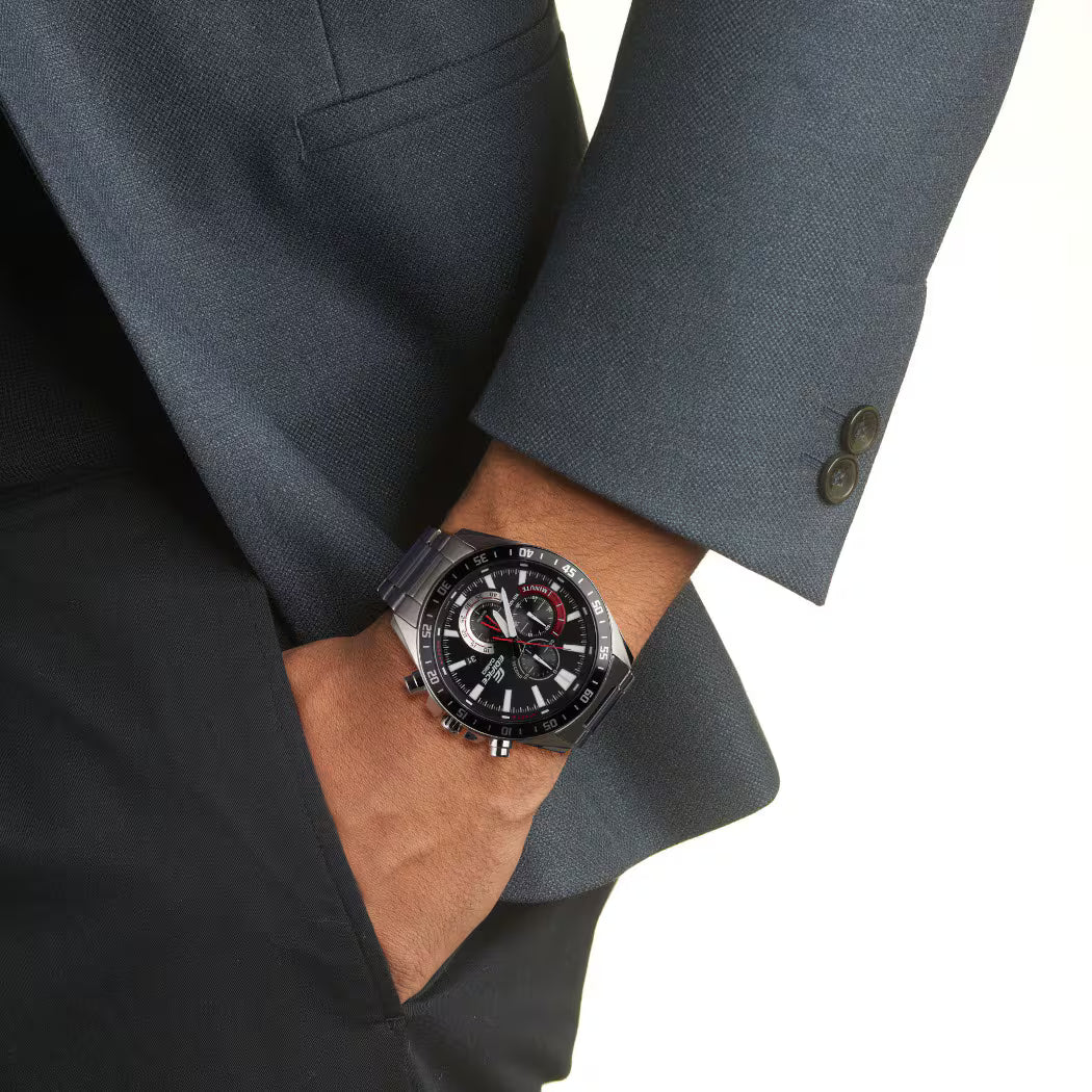 Reloj Casio Edifice de acero con esfera negra y detalles rojos lucido en la muñeca con un traje oscuro.