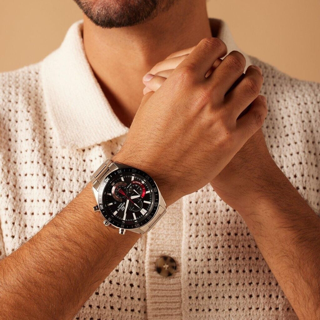 Reloj Casio Edifice de acero con esfera negra y detalles rojos lucido en la muñeca de una persona.