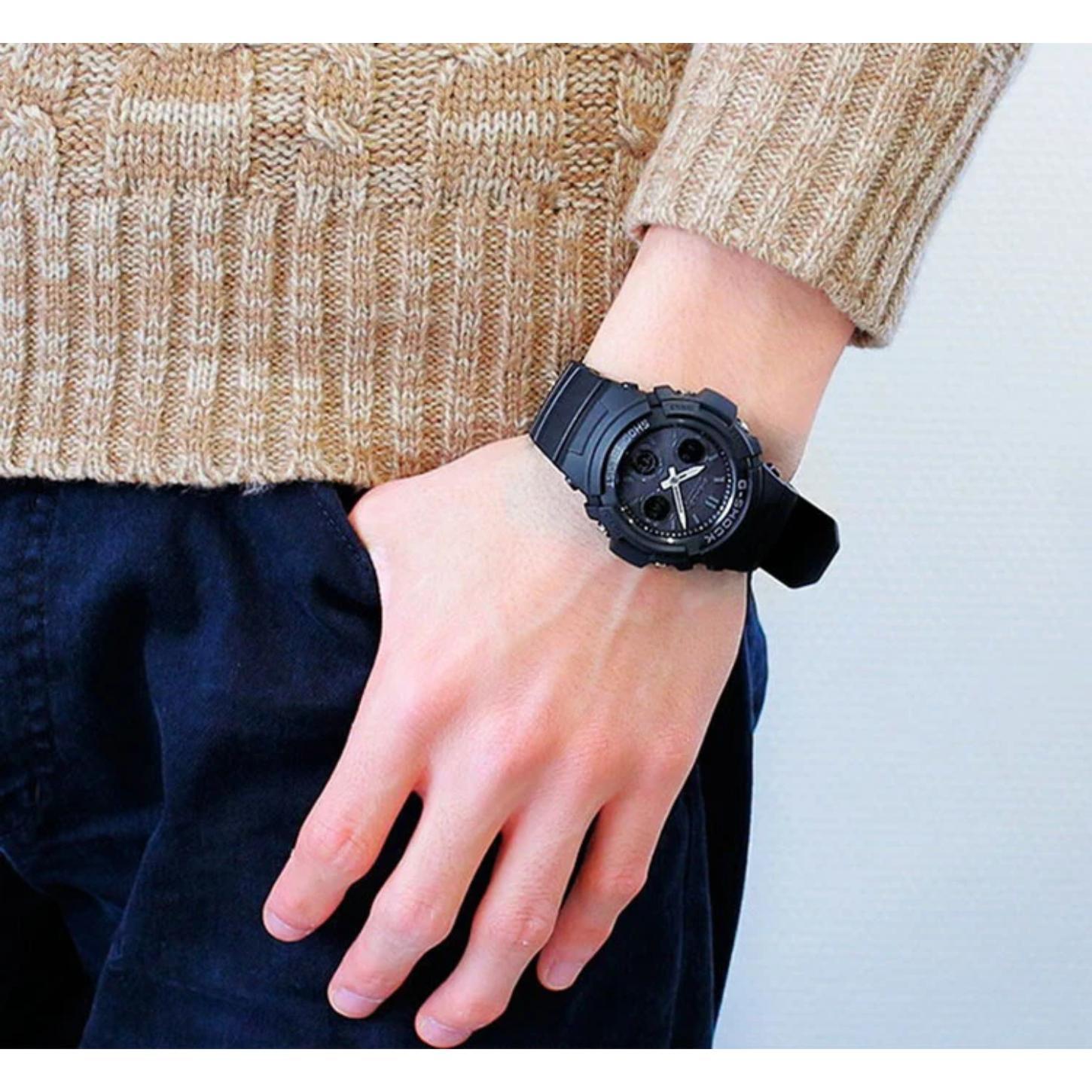 Casio G-Shock AWG-M100B-1A worn on the wrist with a black analog-digital dial, silver-tone hands, rugged black resin case, and matching resin band.