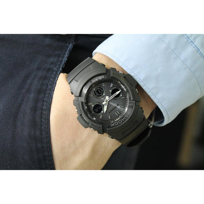Casio G-Shock AWG-M100B-1A worn on the wrist with a black analog-digital dial, silver-tone hands, rugged black resin case, and matching resin band.