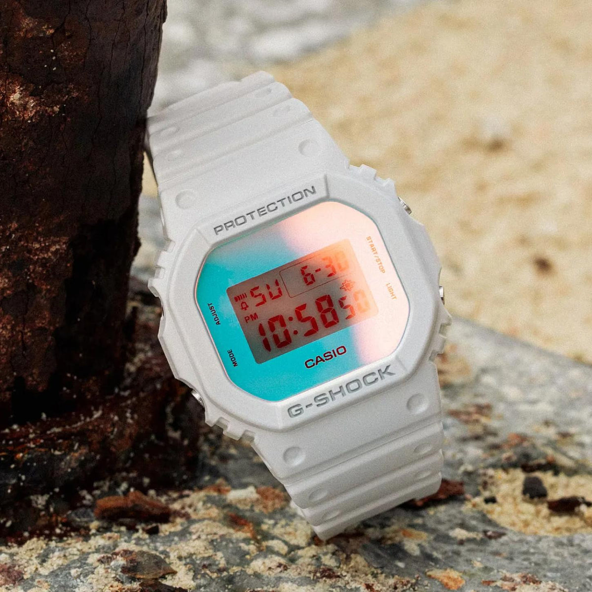 Casio G-Shock DW-5600TL-7 men’s digital watch with a white resin case and strap, square digital display, and iridescent color-shifting dial with turquoise and peach tones.