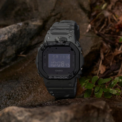 Casio G-Shock DW-5610UU-8DR men’s digital watch with a dark gray resin case and strap, square negative digital display, and visible water droplets on the bezel and band.