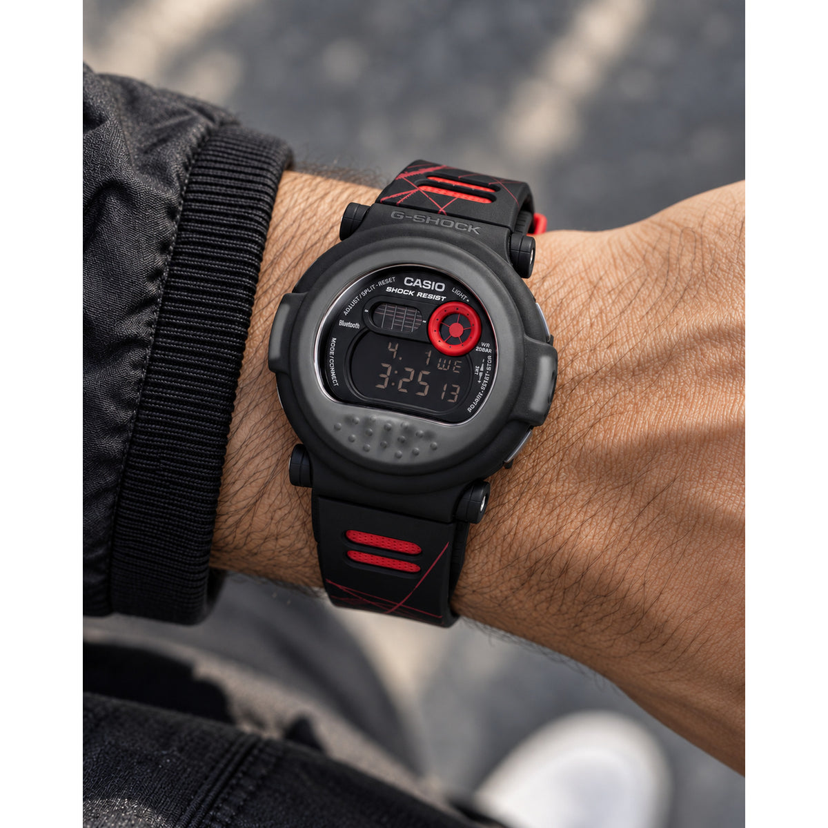 Casio G-Shock G-B001MVA-1DR men’s digital watch with a black rounded case, negative digital display, red accent details, and a black strap worn on the wrist.
