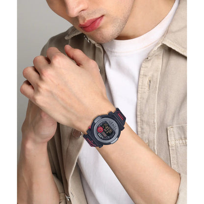 Casio G-Shock G-B001MVA-1DR men’s digital watch with a black rounded case, red accent details, negative digital display, and black patterned strap worn on the wrist.