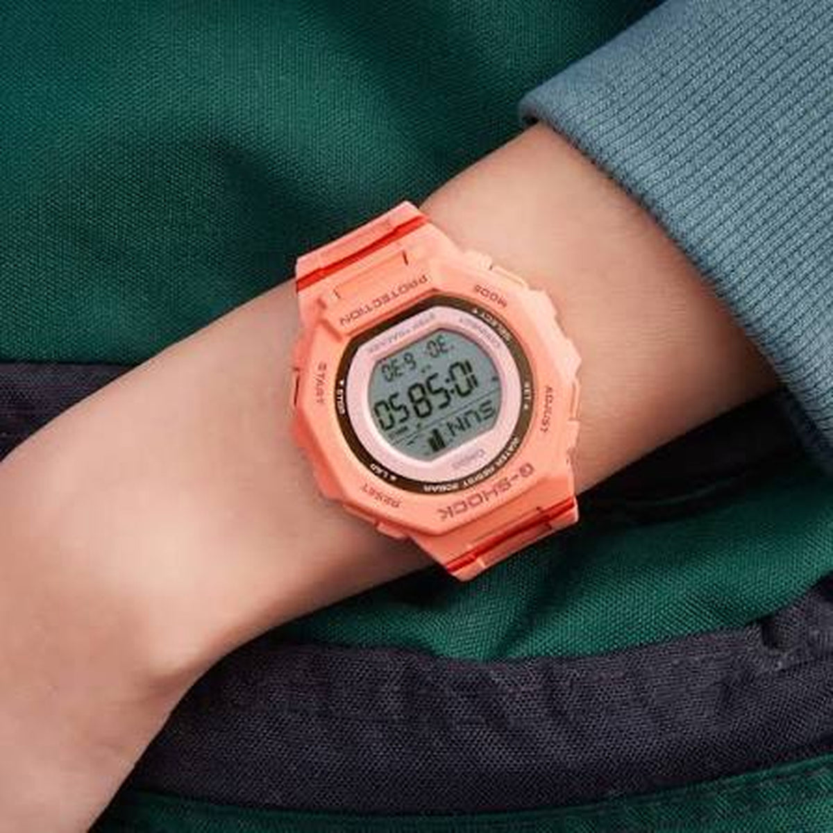 Casio G-Shock G-Squad GMD-B300SC-4DR women’s digital sport watch with a coral-tone case and strap, round digital display, and red accent details worn on the wrist.