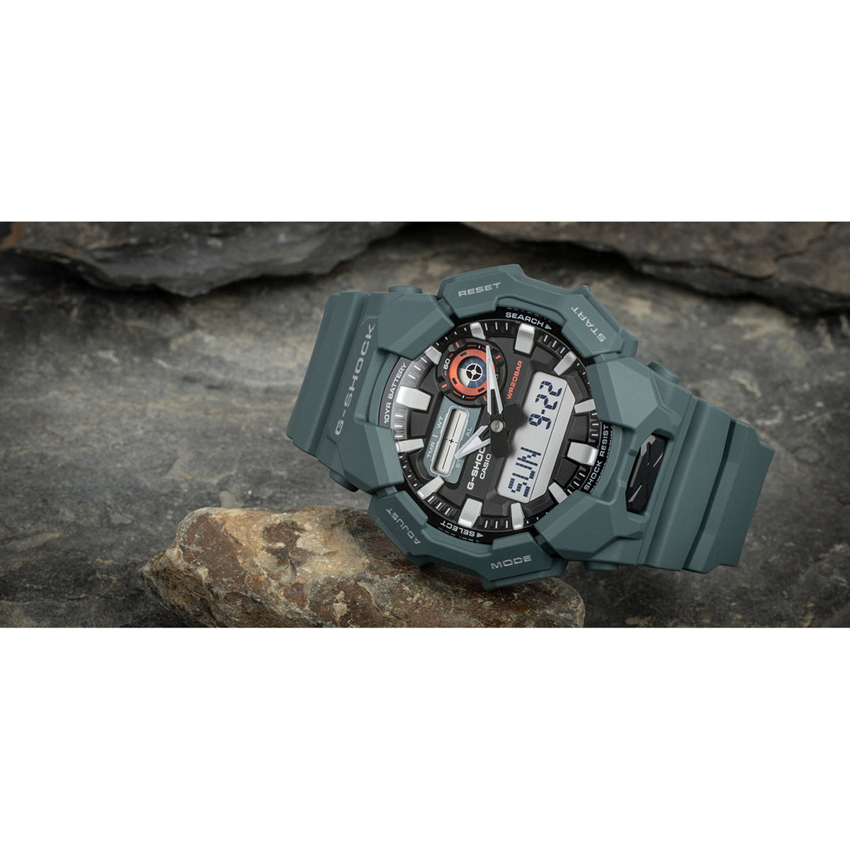 Casio G-Shock GA-010-2A with a black analog-digital dial, bold silver-tone hour markers, red accents, and a dark green resin case and strap.