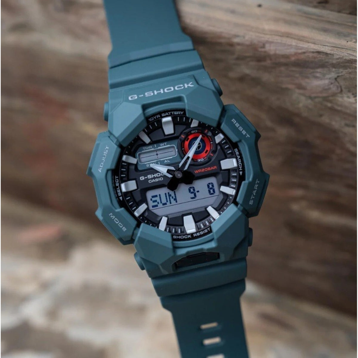 Casio G-Shock GA-010-2A with a black analog-digital dial, silver-tone hour markers, red accents, and a dark green resin case and strap.