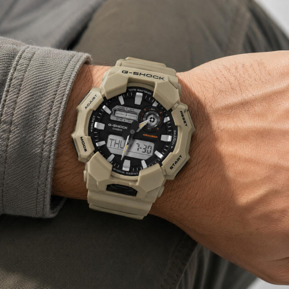 Casio G-Shock GA-010-5A men’s ana-digi watch with a black dial, dual digital displays, orange accents, rugged beige case, and matching beige resin strap worn on the wrist.