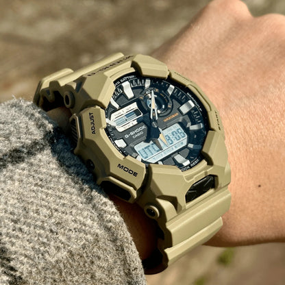 Casio G-Shock GA-010-5A men’s ana-digi watch with a black dial, dual digital displays, rugged beige case, and matching beige resin strap worn on the wrist.