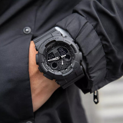Casio G-Shock GA-100-1A1 worn on the wrist, featuring an all-black analog-digital display, shock-resistant resin case, resin strap, and rugged tactical design.