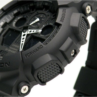 Close-up of the Casio G-Shock GA-100-1A1 showing the black shock-resistant bezel, textured control buttons, analog-digital dial, and rugged resin case details.