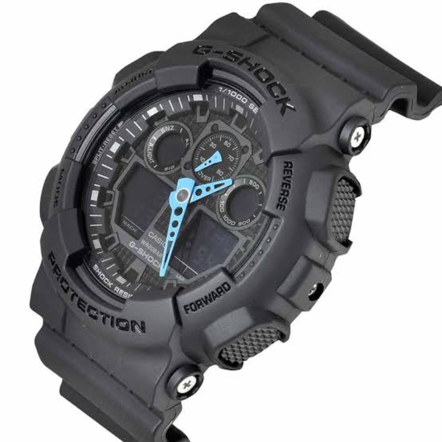 Angled view of the Casio G-Shock GA-100C-8A showing the gray shock-resistant resin case, blue hands, dark analog-digital dial, textured buttons, and protective bezel.