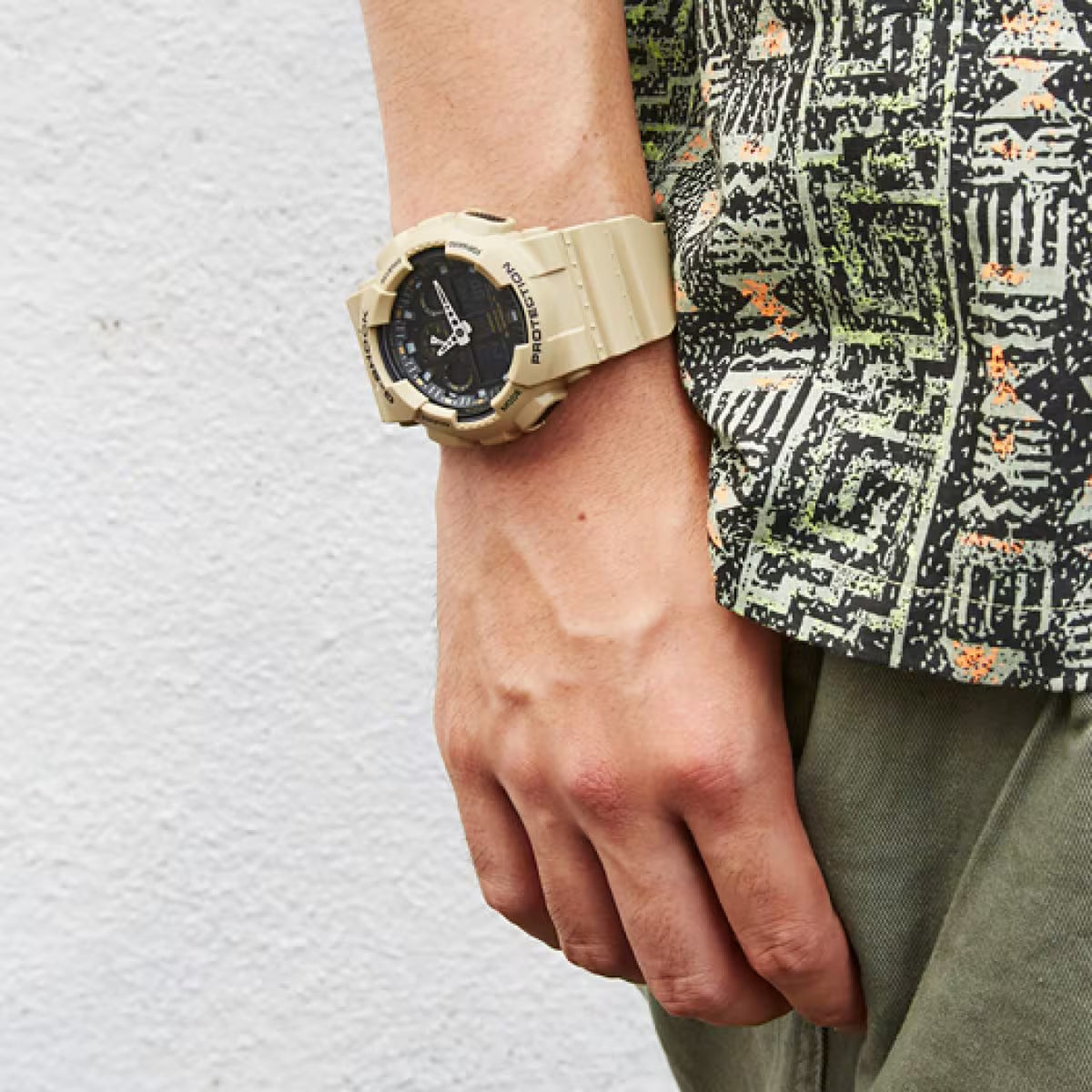 Casio G-Shock GA-100L-8A rugged timepiece worn casually on the wrist with a patterned shirt.