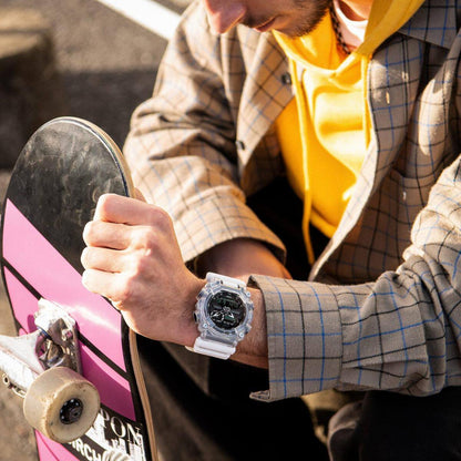 Casio G-Shock GA-900SKL-7ADR worn by a skateboarder, featuring a transparent resin case, black analog-digital dial, and white resin strap.