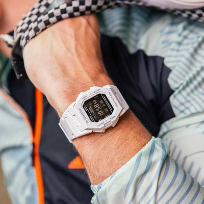 Casio G-Shock GD-B500-7 digital sport watch worn on the wrist during an outdoor activity, featuring a white resin case, black digital display, and white resin strap.
