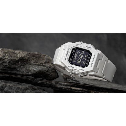 Casio G-Shock GD-B500-7 digital sport watch displayed on rocks, featuring a white resin case and strap, black digital display, and rugged shock-resistant design.