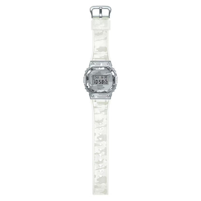 Full length flat lay of the Casio G-Shock GM-5600SCM-1 digital watch, highlighting the complete translucent camouflage strap and square silver-tone case.