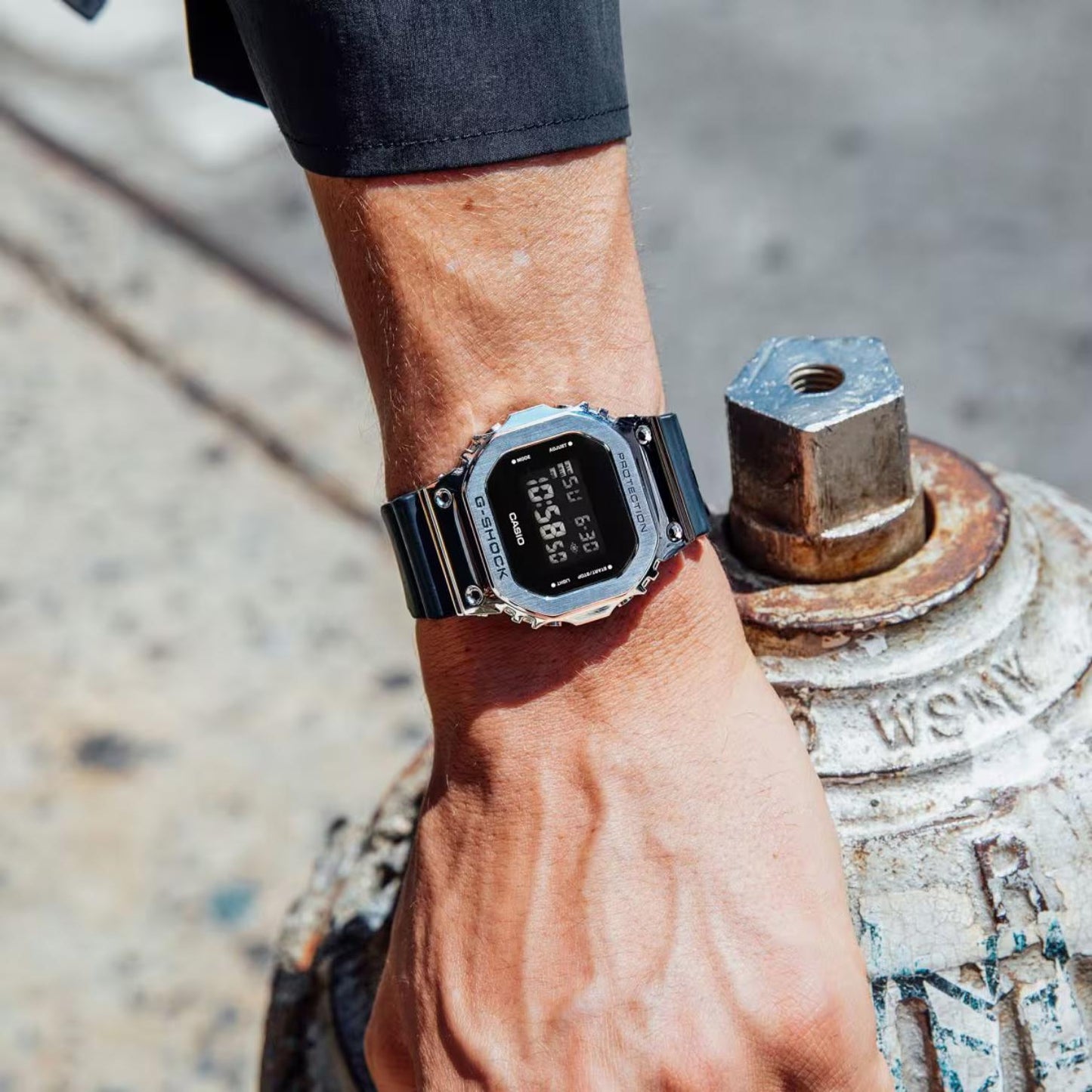 Casio G-Shock GM-5600U-1 worn on the wrist with a rectangular digital display, stainless steel bezel, and black resin band.