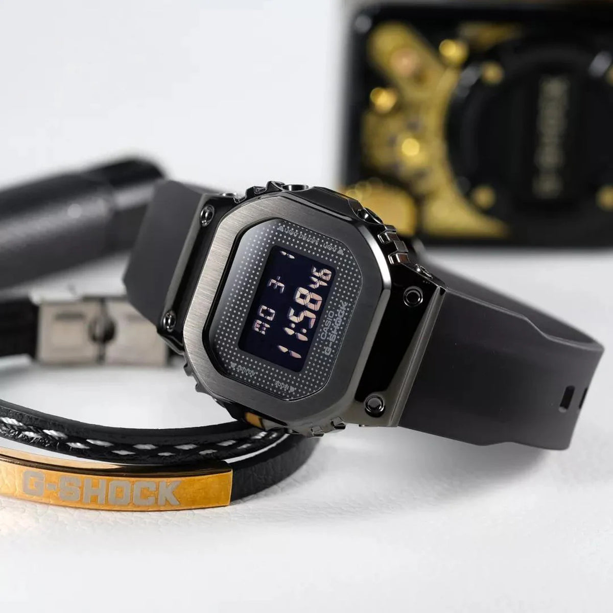 Casio G-Shock GM-S5600SB-1 women's digital watch displayed flat alongside decorative G-Shock branded accessories