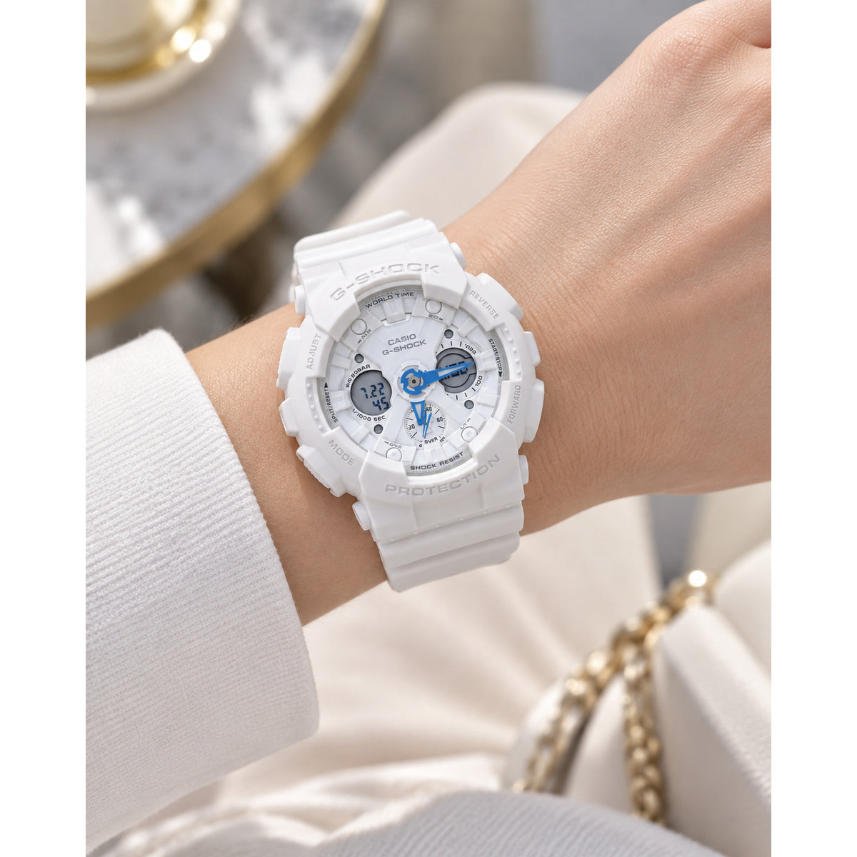 Casio G-Shock GMA-S120SA-7A2DR women's sport watch worn on wrist, featuring a white resin case and strap, white dial, and bright blue hands.