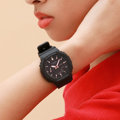 Casio G-Shock GMA-S2100-1A with a black octagonal case, black dial, rose gold-tone hands and hour markers, and a matching black resin strap worn on the wrist.