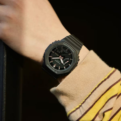 Casio G-Shock GMA-S2100-1A with a black octagonal case, black dial, rose gold-tone hands and hour markers, and a matching black resin strap worn on the wrist.