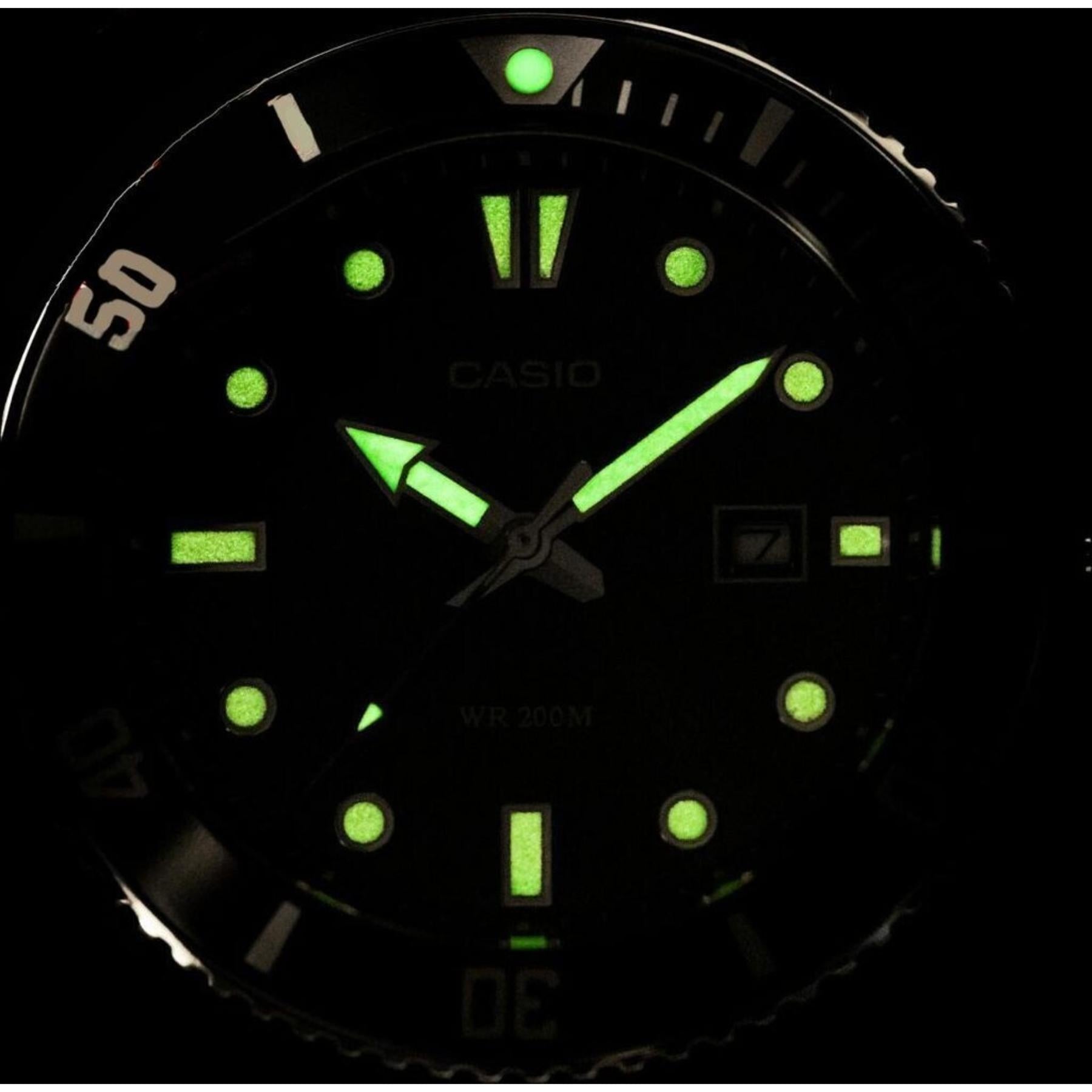 Casio MDV-107D-3A stainless steel dive watch with glowing luminous hands and markers displayed in dark lume close-up view.