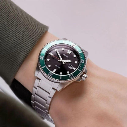 Casio MDV-107D-3A stainless steel dive watch worn on wrist with black dial, green unidirectional bezel and stainless steel bracelet.