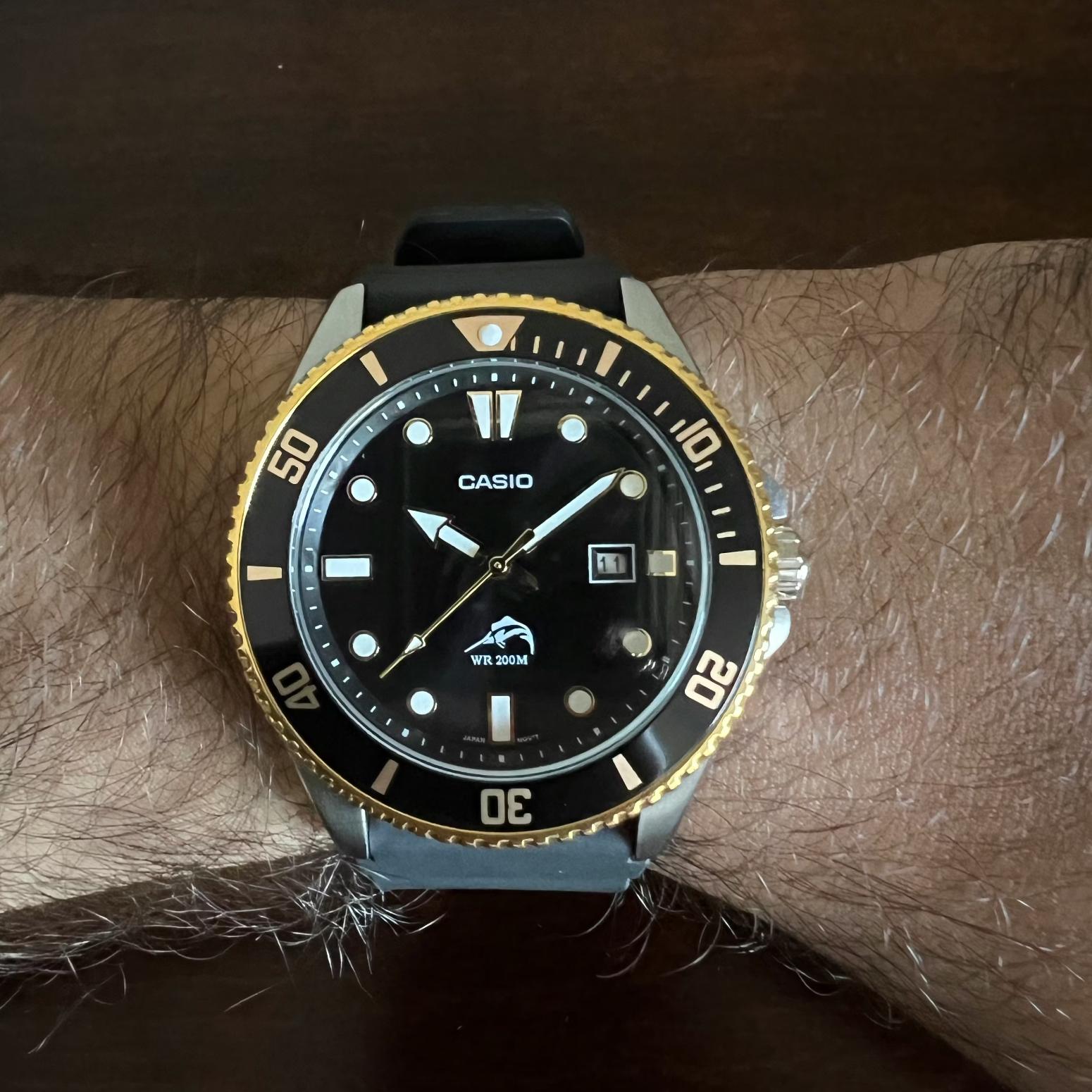 Casio MDV106G-1AV quartz dive watch with black dial, gold tone rotating bezel and black rubber strap worn on wrist with sporty design