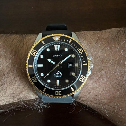 Casio MDV106G-1AV quartz dive watch with black dial, gold tone rotating bezel and black rubber strap worn on wrist with sporty design